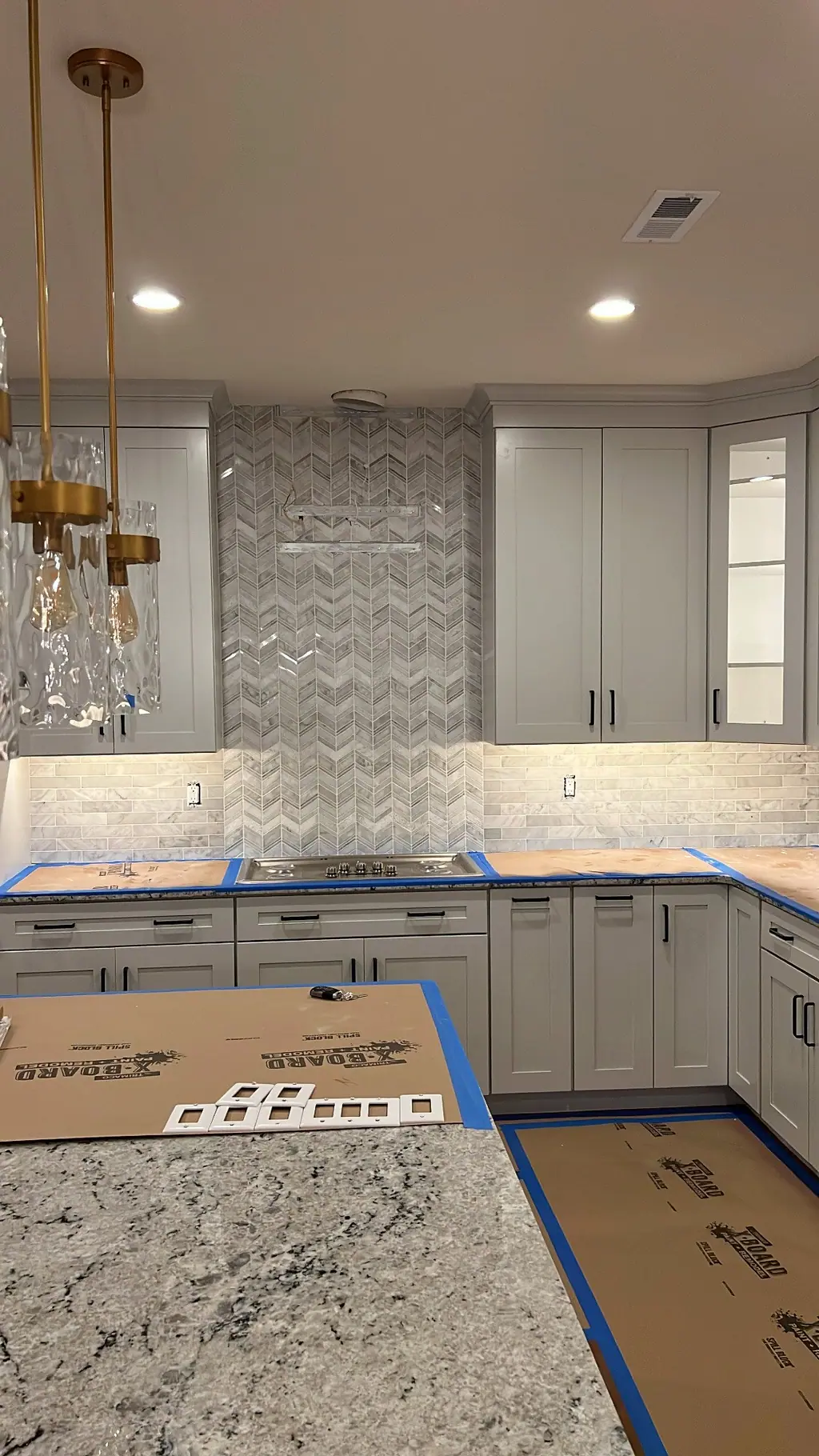 Gray shaker kitchen with marble herringbone range wall and brass pendant